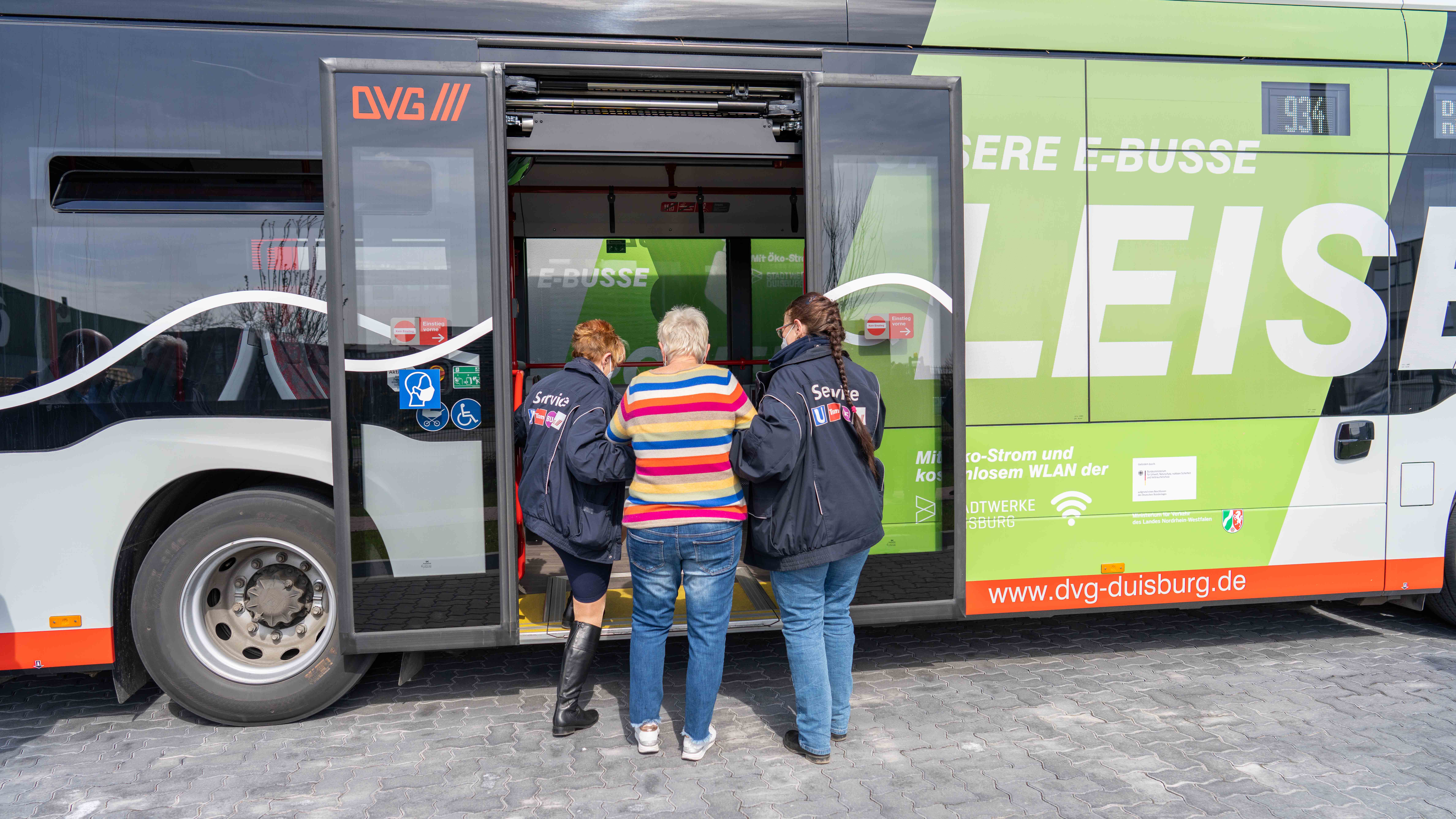 Zwei Servicekräfte helfen Fahrgast beim Einstieg in DVG-Bus