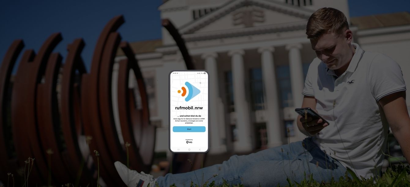 Smartphone zeigt die rufmobil.nrw-App, während eine Person im Freien auf ihr Handy schaut