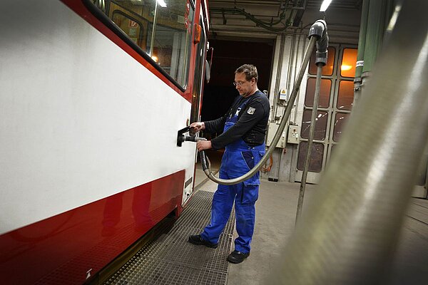 Mitarbeiter befüllt Straßenbahn mit Bremssand