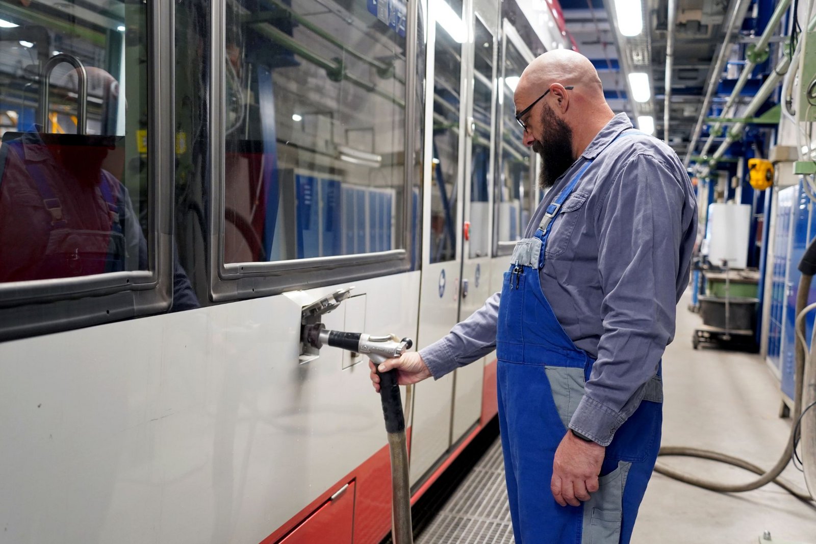 Werkstattmitarbeiter befüllt eine DVG-Straßenbahn auf dem Betriebshof Grunewald mit Quarzsand.