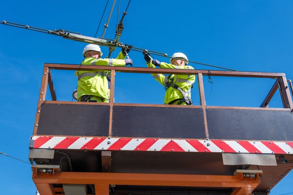 Zwei Fachkräfte der DVG arbeiten an der Oberleitung der Straßenbahn.